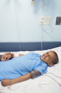 African boy laying in hospital bed wincing