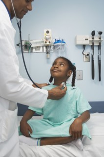 Young African girl being examined by doctor in hospital room