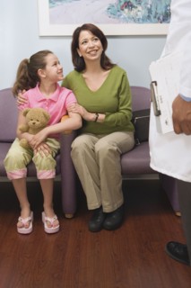 Hispanic mother and daughter talking to doctor in waiting room
