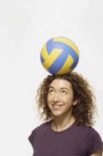 Mixed Race woman balancing volleyball on head