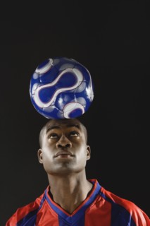 African American man balancing soccer ball on head