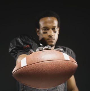 African American male football player holding out football