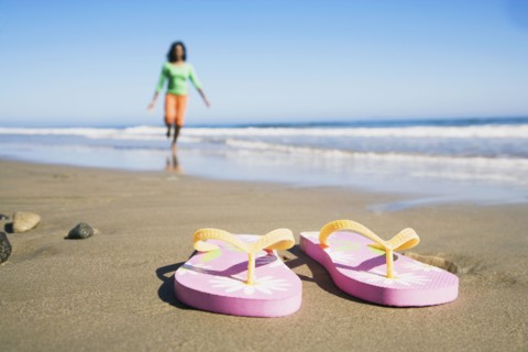 Flip-flops on beach in front of woman
