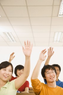 Chinese students with arms raised in classroom