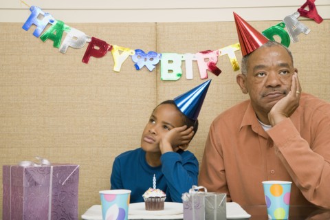 African boy with grandfather and cupcake at birthday party