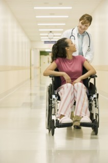 Doctor pushing patient in hospital hallway