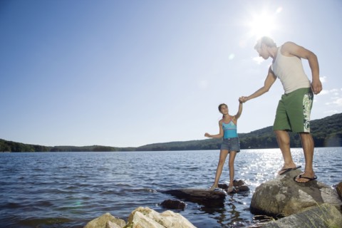 Father and daughter standing by lake