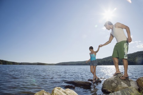 Father and daughter standing by lake