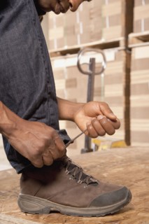 Black man tying shoes in warehouse
