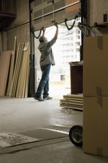 Black man closing loading dock door in warehouse