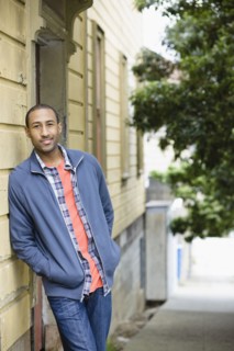 African American man leaning against side of building