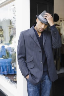 African American man standing in shop doorway with fedora