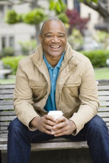 Mixed race man drinking coffee in park