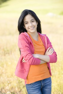 Hispanic girl in field with arms crossed