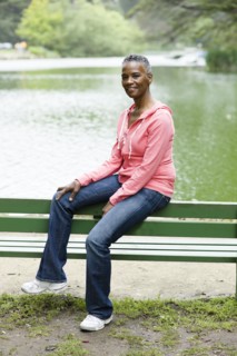 African American woman sitting on park bench near lake