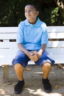 Smiling mixed race boy sitting in park