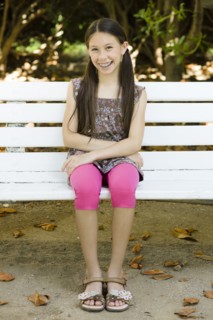Smiling mixed race girl sitting on park bench
