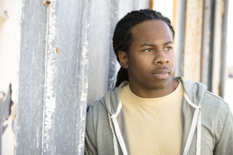 Serious Black man leaning against wall