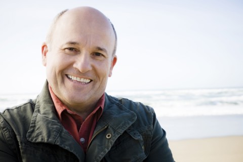 Smiling Caucasian man standing on beach