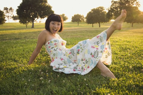 Asian woman kicking up foot in grass