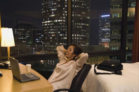 Hispanic woman looking at laptop in hotel room