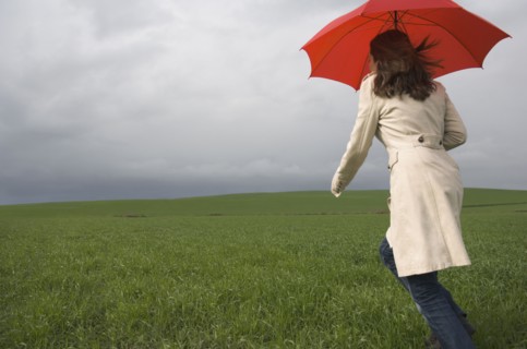 Rear view of woman running with umbrella in field