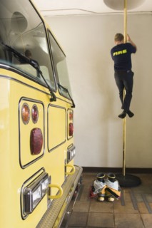 Male firefighter sliding down pole