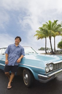 Asian man leaning on car