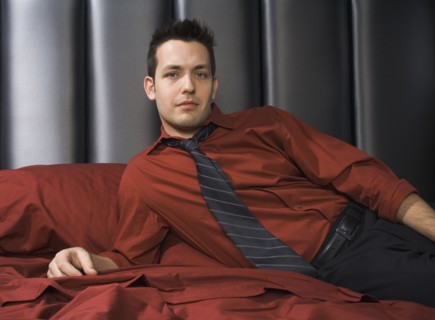 Man wearing shirt and tie on bed