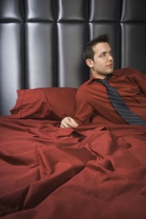 Man wearing shirt and tie on bed