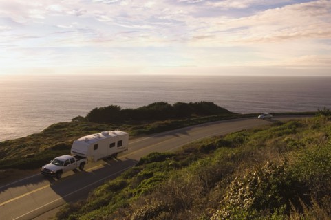 Truck pulling camper on coastal highway