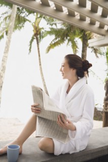 Asian woman in bathrobe reading newspaper