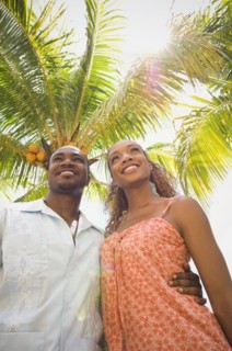 African American couple hugging under palm tree