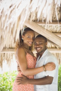 African American couple hugging in grass hut
