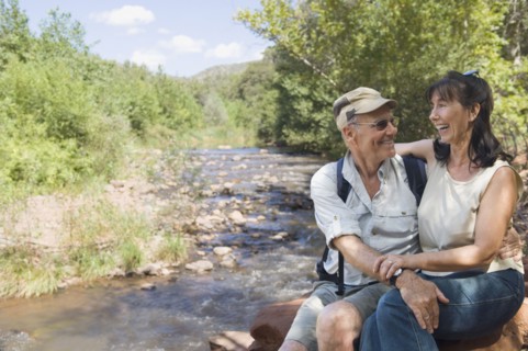 Multi-ethnic senior couple hugging next to stream
