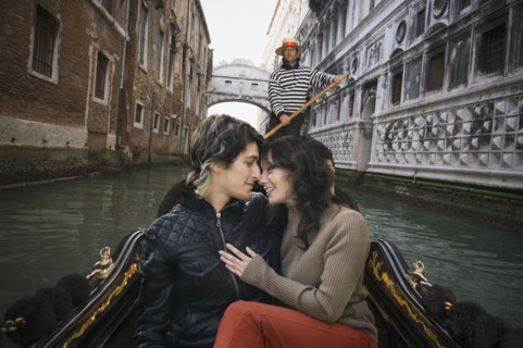 Romantic Italian couple riding in gondola through canal