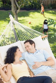 Couple in hammock with children playing in background