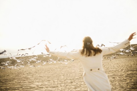 Woman scaring seagulls on beach