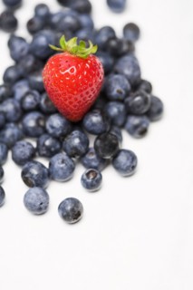 Strawberry on pile of blueberries