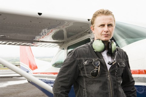 Caucasian pilot standing near small airplane