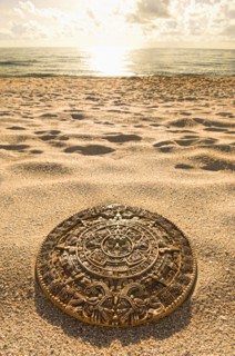 Aztec calendar stone carving on sandy beach