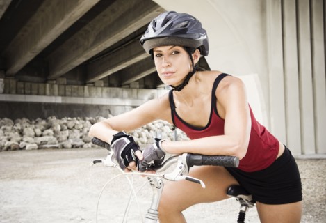 Hispanic woman sitting on bicycle in urban area