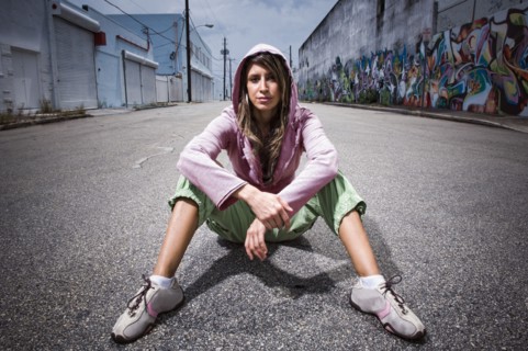 Hispanic woman sitting in alley with graffiti