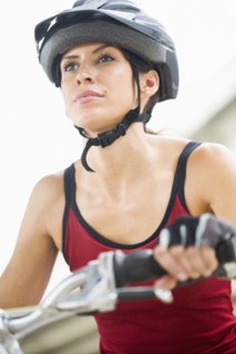 Hispanic woman in helmet riding bicycle