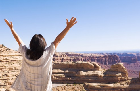 Hispanic woman cheering near canyon