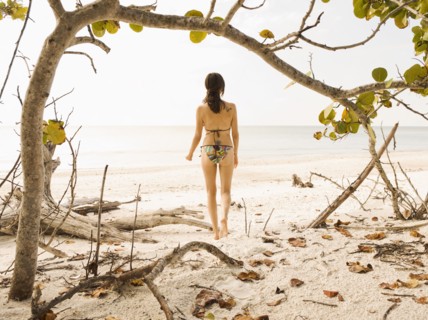 Hispanic woman in bikini standing on beach