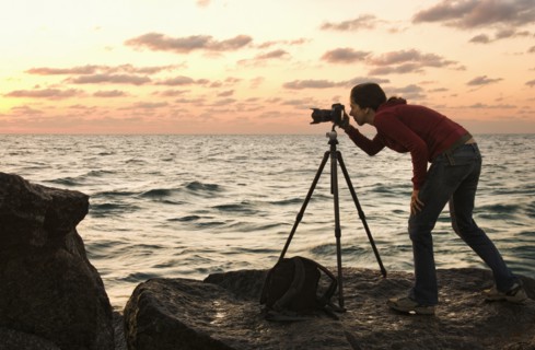 Mixed race woman using camera near ocean