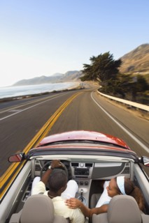 Couple driving convertible on coastal road