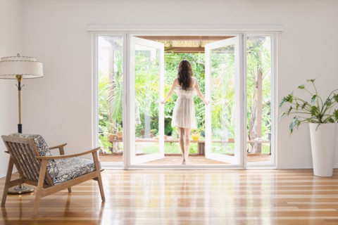 Hispanic woman opening French doors to patio