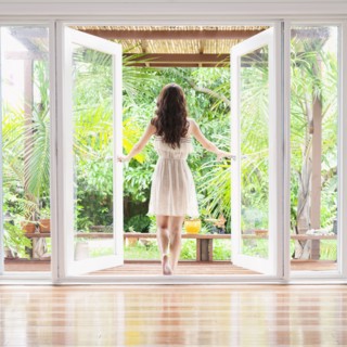 Hispanic woman opening French doors to patio